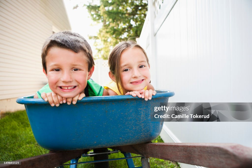 Brother and sister in a wheel barrel smiling