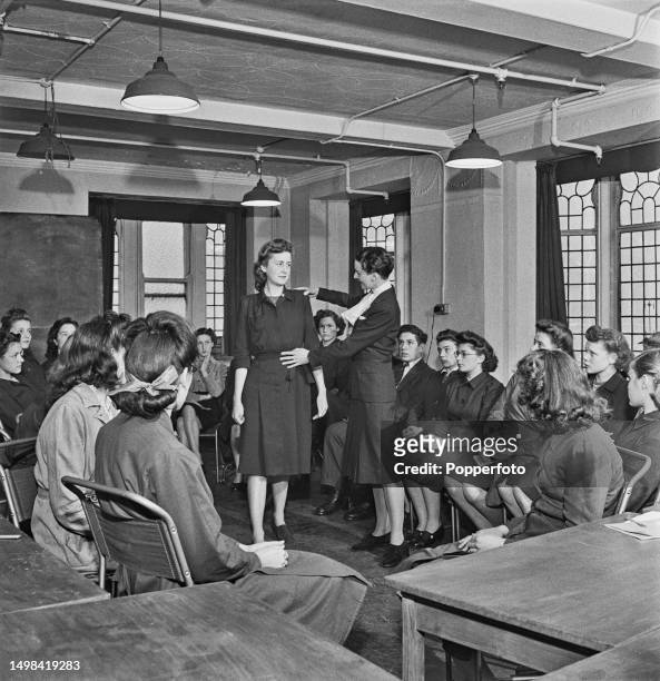 Miss Dalziel teaches the art of deportment to trainee female store assistants in a staff training room at the Peter Jones Department Store, part of...