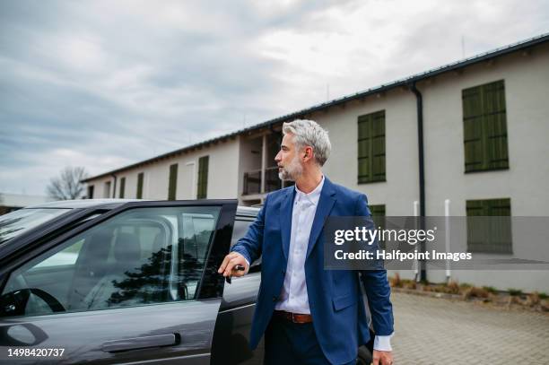 businessman with luggage getting out of a car. - expensive car stock pictures, royalty-free photos & images