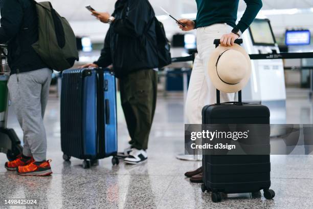 cropped shot of group of airline passengers with suitcases standing in queue, waiting at check-in counter at international airport. ready for a trip. business travel. travel and vacation concept - lining up stock pictures, royalty-free photos & images