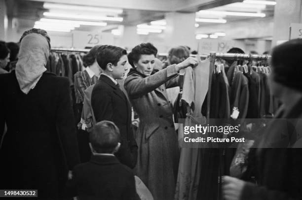Shoppers browse women's clothes in a department store during a winter sale, Britain, January 1950. Original Publication: Picture Post - 4966 - Women...