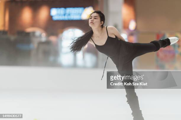 asian female figure skater in black leotard practicing her skate routines - indoor ice rink stock pictures, royalty-free photos & images