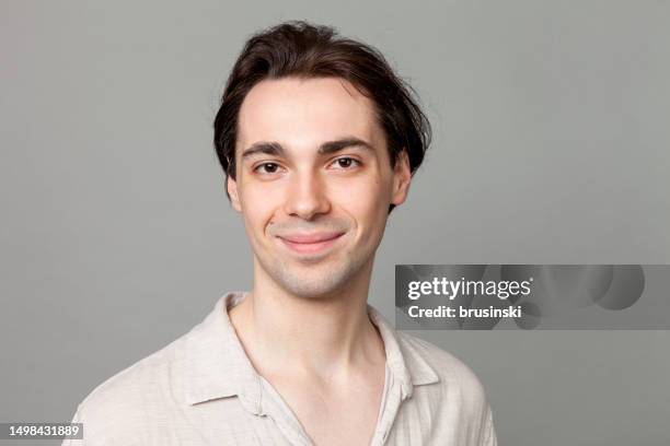 studio portrait of a young white men in a beige shirt against a gray background - handsome hunks stock pictures, royalty-free photos & images