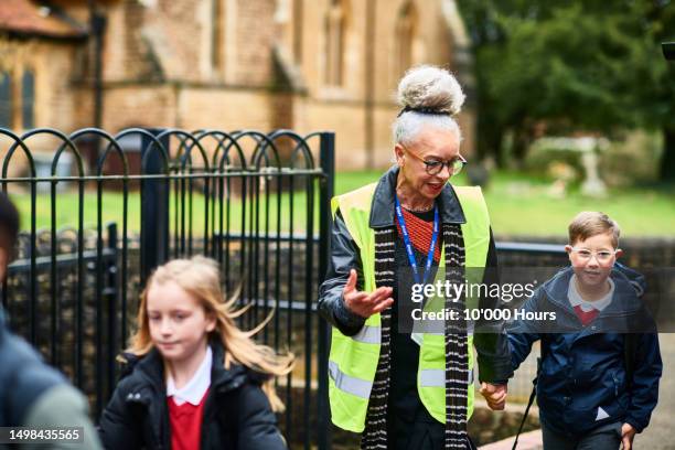 senior woman in hi vis accompanying boy with down syndrome into school - accompanying stock pictures, royalty-free photos & images