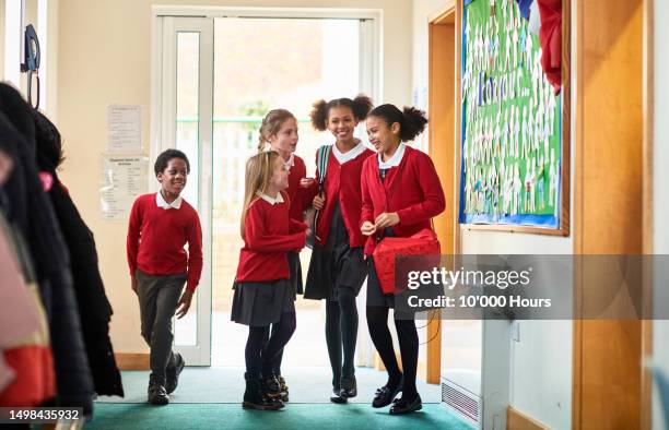 group of excited school children arriving in school building, talking and smiling - girl in uniform stock pictures, royalty-free photos & images