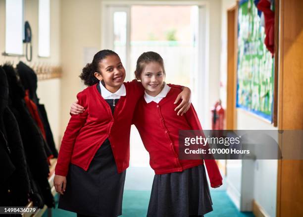 portrait of two female friends in school corridor with arms around each other - unforgettable stock pictures, royalty-free photos & images
