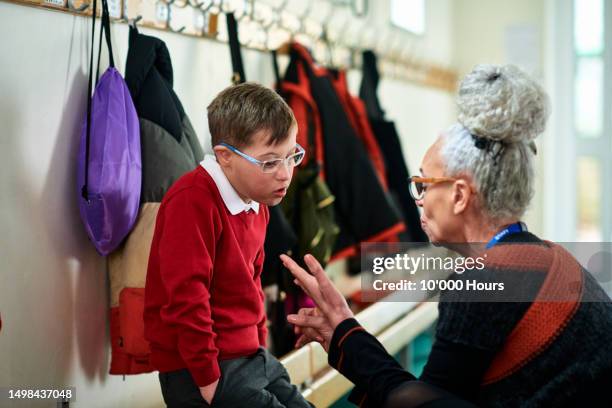 primary school teacher supporting boy with down syndrome in school corridor - dialogue stock pictures, royalty-free photos & images