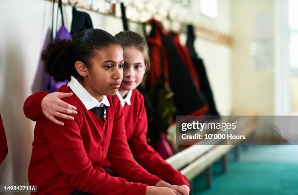 girl consoling school friend with arm around her - child mental health wellness stock-fotos und bilder