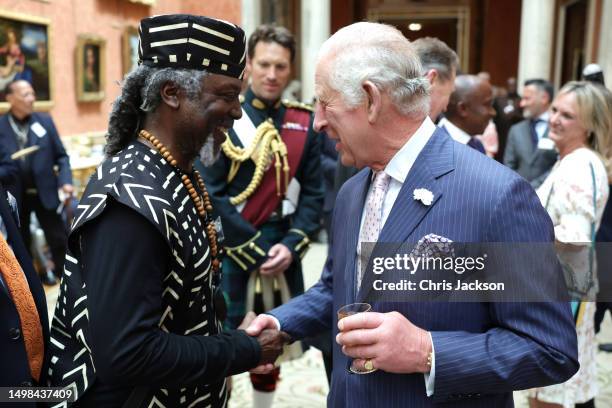 King Charles shakes hands with guest during a reception to mark the 75th anniversary of the arrival of HMT Empire Windrush at Buckingham Palace on...