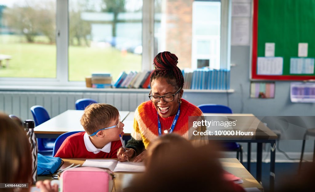 School teacher smiling and laughing with boy with Down syndrome