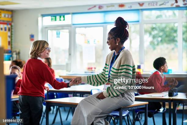 female elementary school teacher playing game with school boy, smiling - welcome back phrase imagens e fotografias de stock