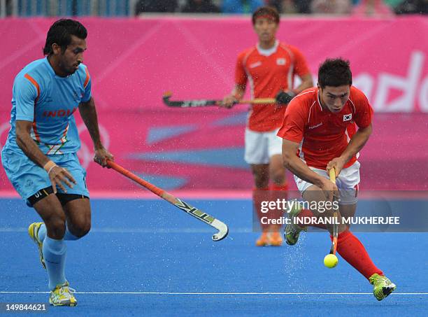 Dharamvir Singh of India vies for the ball with You Hyosikof South Korea during the men's field hockey preliminary round match between India and...