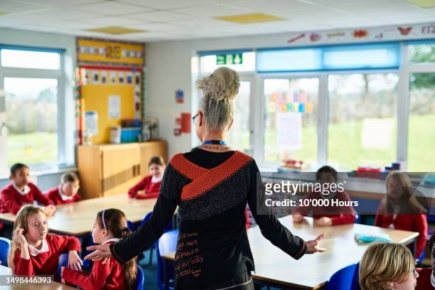 primary school teacher standing with arms out, preparing children for meditation class - kid stock pictures, royalty-free photos & images