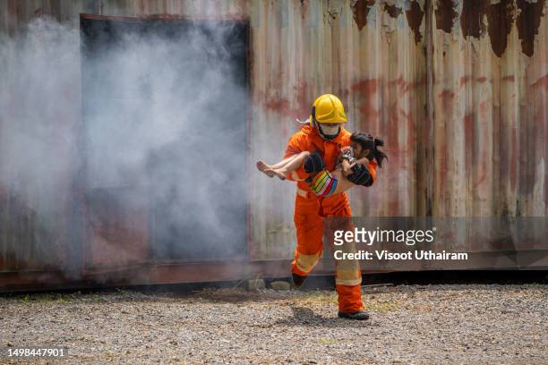 firefighters,burning building,fireman holds saved girl in his arms. - burns victims stock pictures, royalty-free photos & images