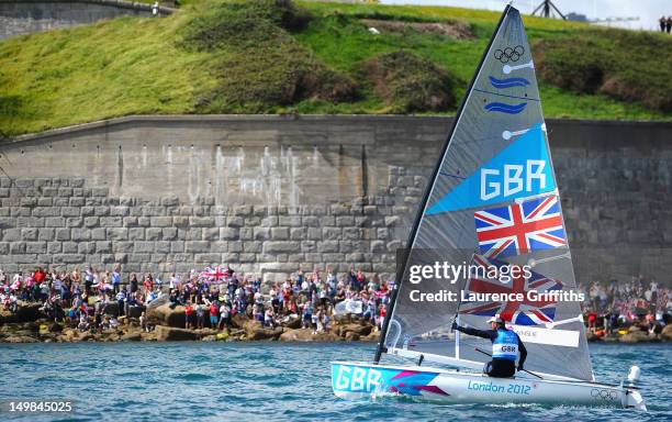 Ben Ainslie of Great Britain celebrates winning gold in the Finn Class Medal race as fans cheer him on from the Nothe at Weymouth Harbour on August...