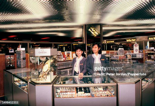 Foreign sales assistants stand ready to serve customers at a watch and jewellery counter in a Duty Free shop at Dubai International Airport in Dubai,...
