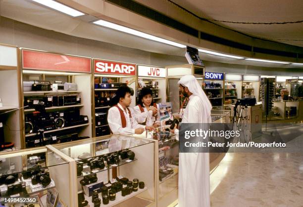 Customer is served by sales assistants at a counter selling electronic goods in a Duty Free shop at Dubai International Airport in Dubai, United Arab...