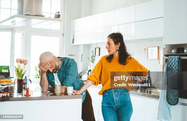 serious woman arguing with man in kitchen at home - ruziemaken stockfoto's en -beelden
