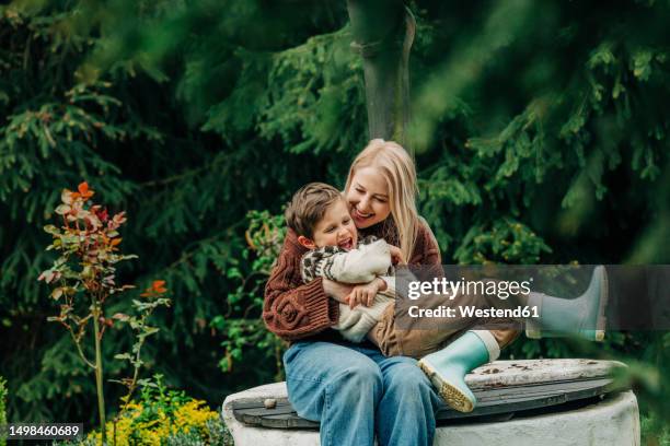 mother with son sitting together on well in garden - tickling stock pictures, royalty-free photos & images