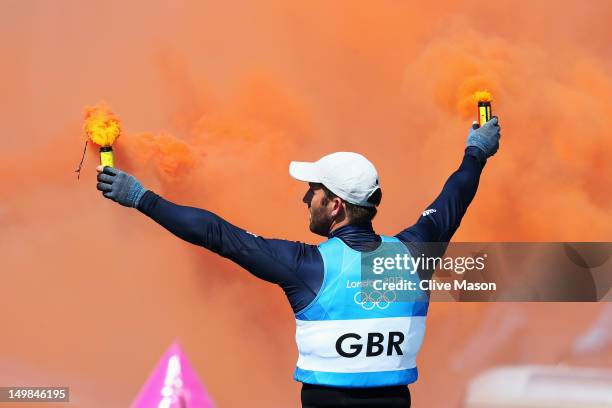 Ben Ainslie of Great Britain lights flares as he celebrates overall victory after competing in the Men's Finn Sailing Medal Race on Day 9 of the...