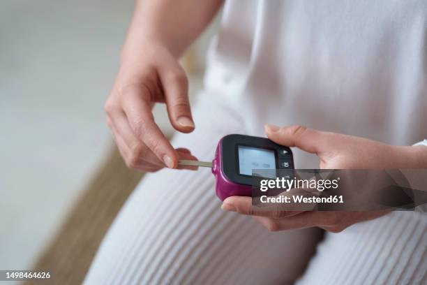 woman holding digital glucometer at home - blood sugar test stock pictures, royalty-free photos & images