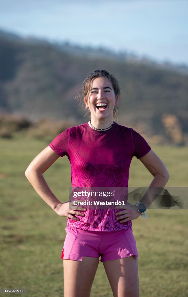 Happy woman standing with arms akimbo