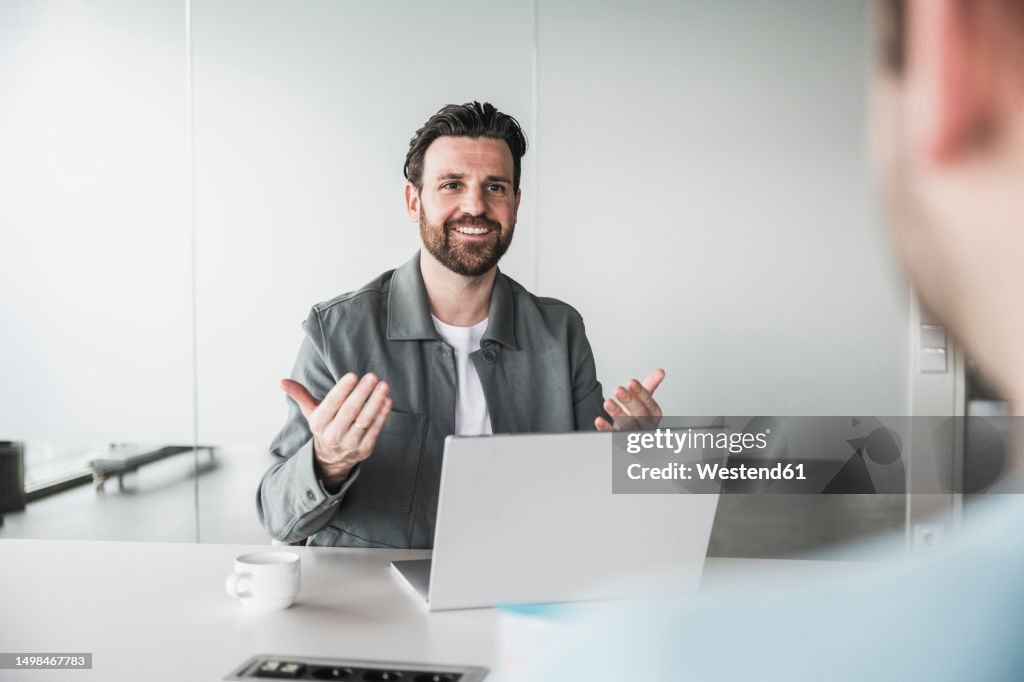 Smiling businessman talking with candidate at office