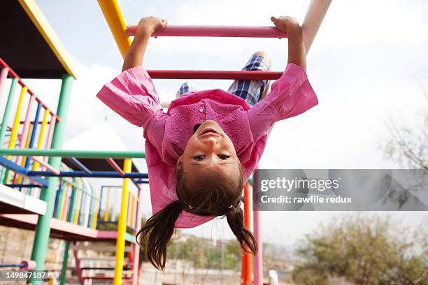 hispanic girl playing in the monkey bars. - upside down ストックフォトと画像