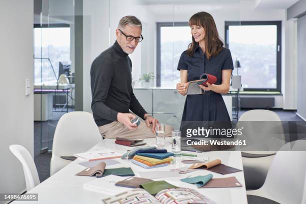 creative businessman and businesswoman discussing swatches in office - fabric swatches imagens e fotografias de stock