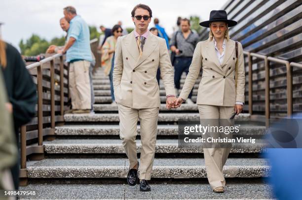 Couple wears beige double breasted blazer, pants, hat during Pitti Immagine Uomo 104 on June 14, 2023 in Florence, Italy.