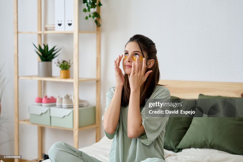Woman applying anti-dark circles patches in her bedroom