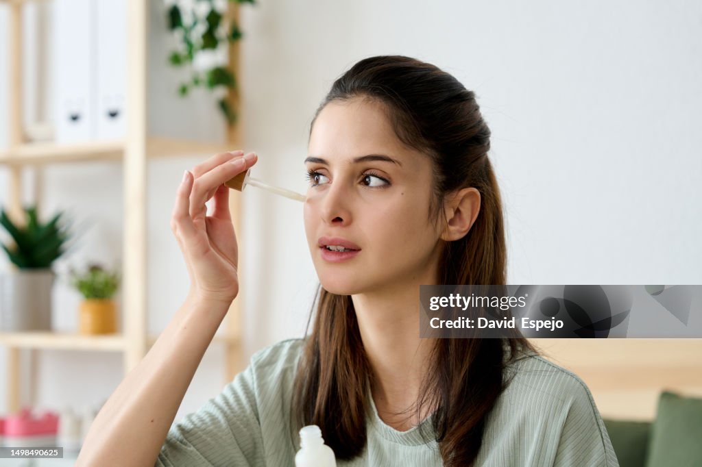 Close-up shot of a young woman applying facial skin care serum