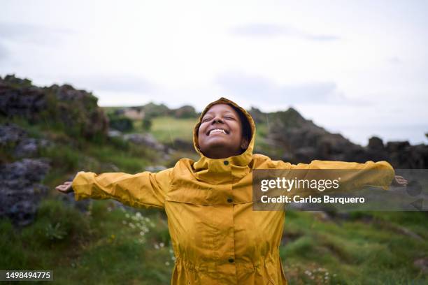 young woman enjoying the rain. - レインコート ストックフォトと画像