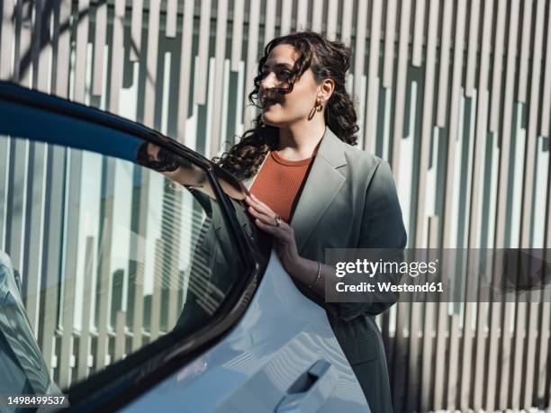 young woman opening car door at sunny day - open car door stock pictures, royalty-free photos & images