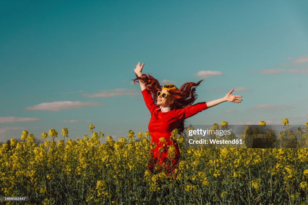 Cheerful woman enjoying with arms outstretched in rapeseed field