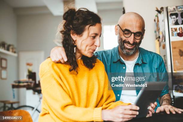 happy couple using tablet pc at home - happy couple at home stockfoto's en -beelden