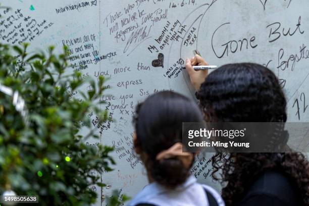 People write messages on the tribute wall outside Grenfell Tower on June 14, 2023 in London, England. A fire broke out in Grenfell Tower, North...