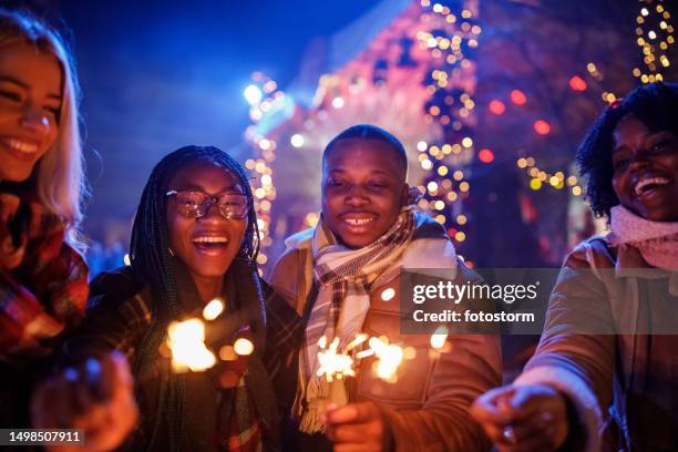 friends at the new year's eve concert dancing and waving sparklers - christmas togetherness stock pictures, royalty-free photos & images