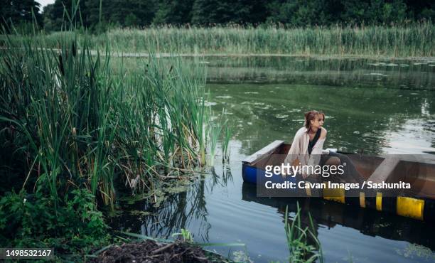 a woman in a boat floats on the river - kroos stockfoto's en -beelden