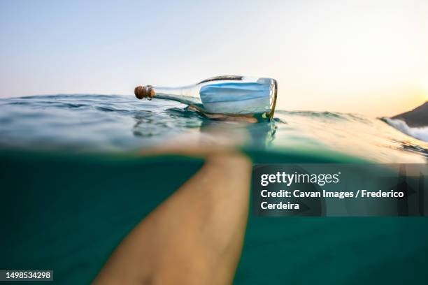 holding a covid-19 surgical face mask inside a glass bottle in the sea - the sea inside stock pictures, royalty-free photos & images