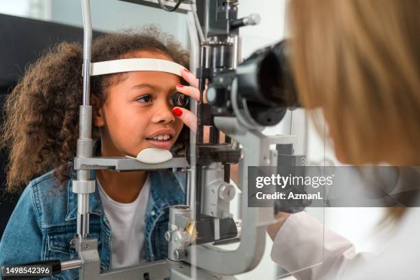 little black child having her right eye checked by professional eye doctor - exame oftalmológico imagens e fotografias de stock