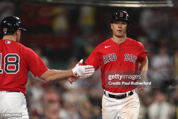 Rob Refsnyder of the Boston Red Sox high fives Adam Duvall after scoring during the seventh inning against the Colorado Rockies at Fenway Park on...