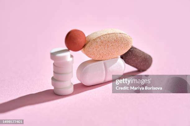 pills, vitamins and nutritional supplements on a pink background are stacked in bizarre figures. - streptomyces antibioticus imagens e fotografias de stock