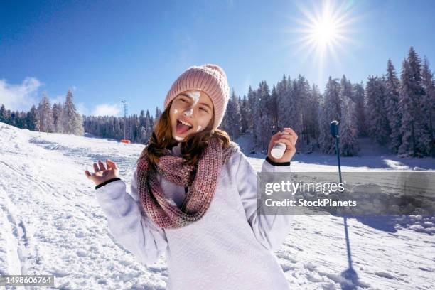 girl protecting skin applying moisturizer cream in a snowy mountain - dry skin stock pictures, royalty-free photos & images