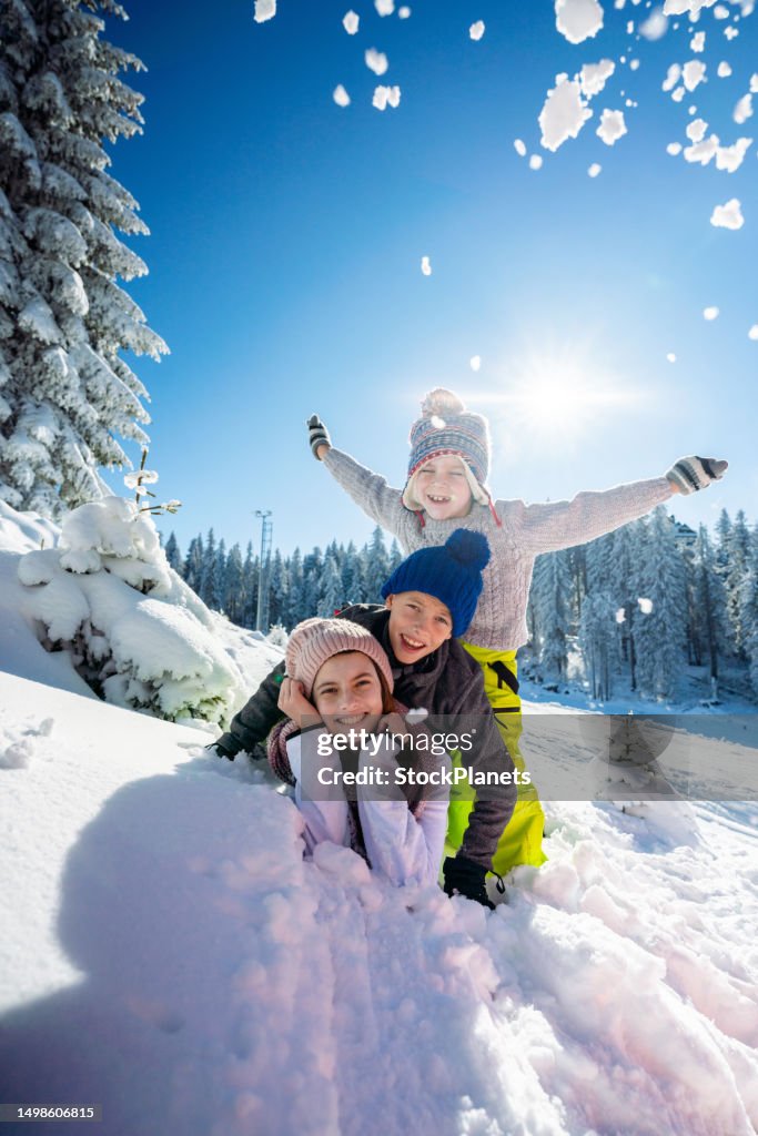 Portrait of three little skier lying on snow and looking at camera