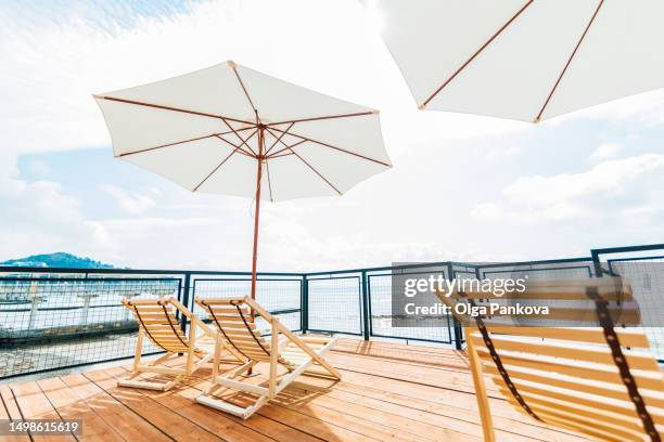 perfect spot for relaxation on a bright and sunny day terrace with sun loungers and parasols - sun deck stock pictures, royalty-free photos & images