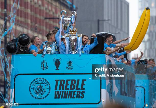 Bernardo Silva of Manchester City celebrates with three trophies on an open top bus along Deansgate after Manchester City win the Premier League, FA...