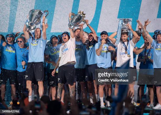 Erling Haaland, Ederson and Ruben Dias of Manchester City celebrate with the three trophies on stage in St Peter's Square during the Manchester City...