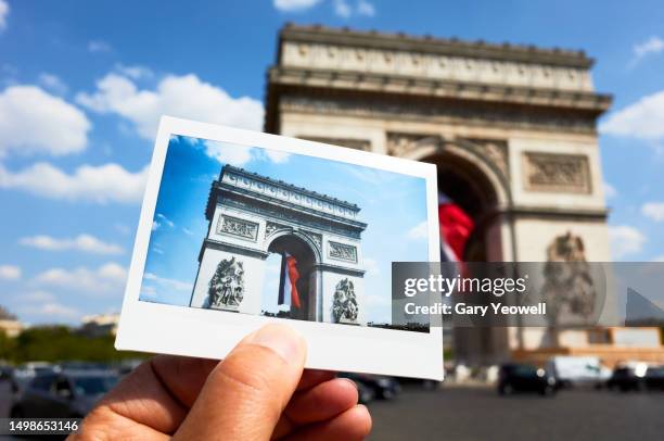 man holding an instant film photo of the arc de triomphe front of the scene - photo de film stock pictures, royalty-free photos & images