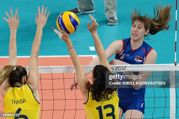 Serbia's Brankica Mihajlovic spikes as Brazil's Sheilla Castro and Thaisa Menezes attempt to block during the Women's preliminary pool B volleyball...